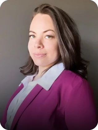 Professional headshot of a woman wearing a magenta blazer and white shirt against a neutral gray background.