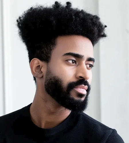 Man with curly hair and beard looking to the side.